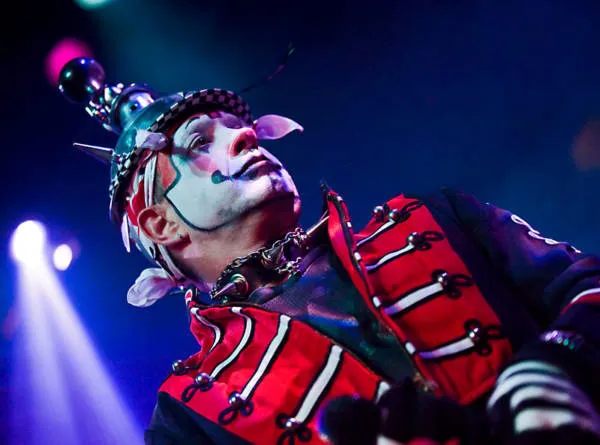 Boenobo in a spiked ringmaster helmet and red braided jacket under stage light