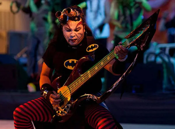 Stitchez playing a horned bass in striped stockings and goggles